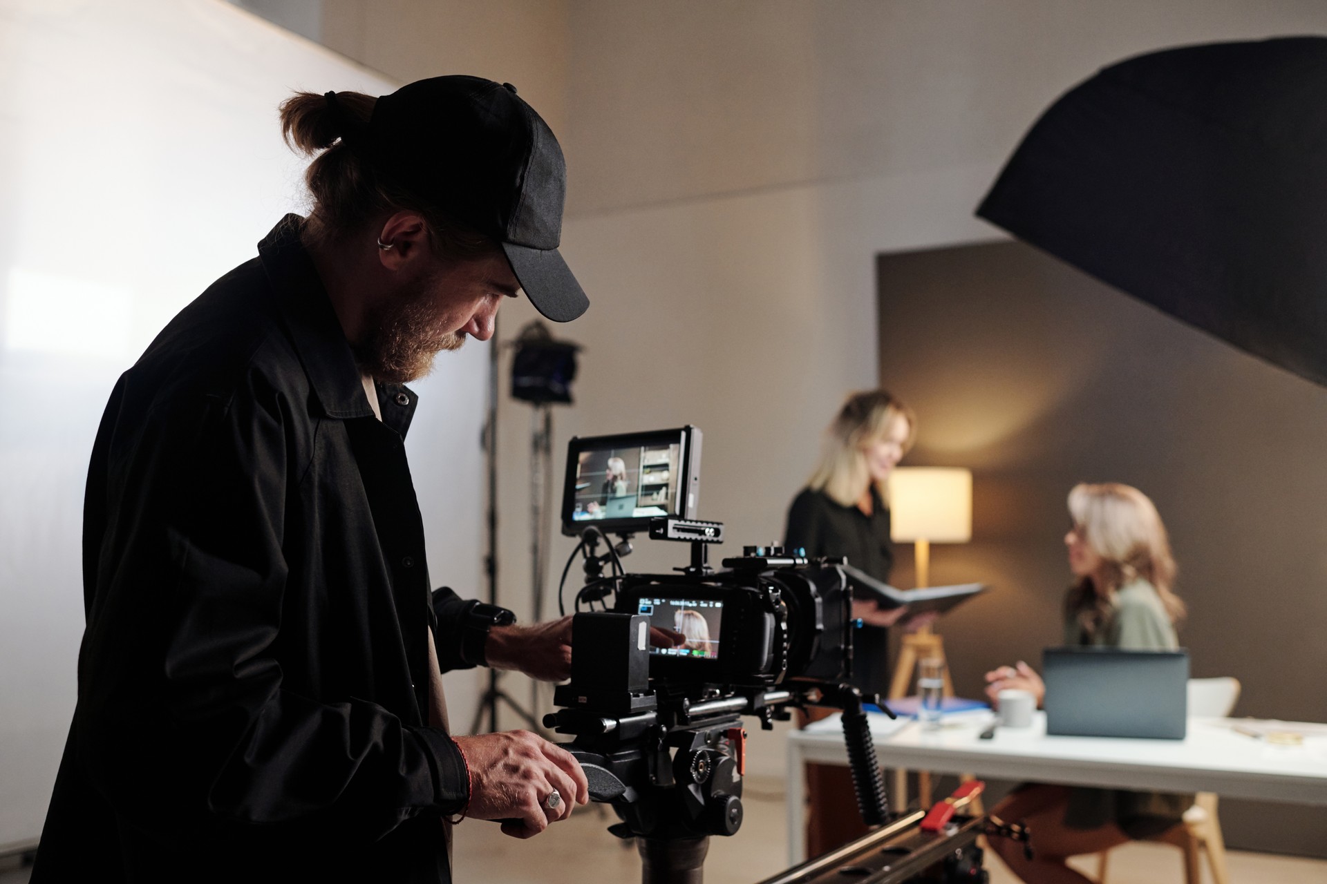 Young serious production studio worker adjusting videocamera during shooting